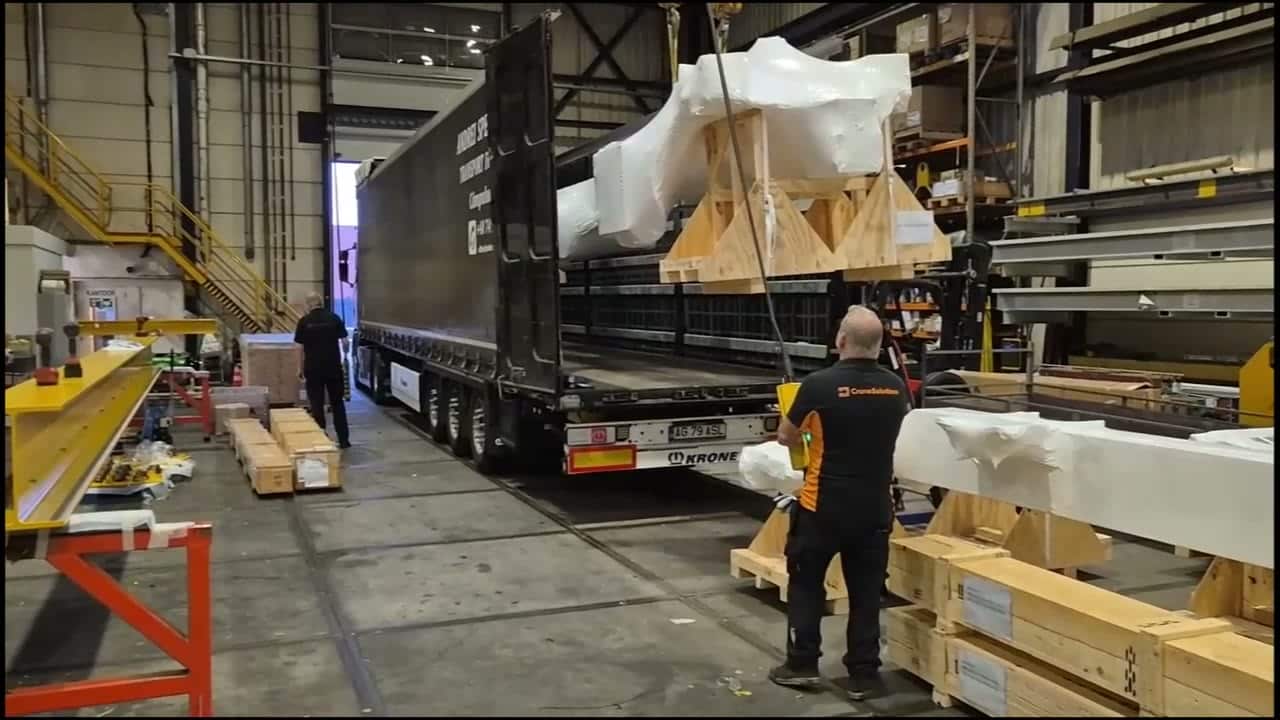Monteur begeleidt een ingepakte kraan die met de bovenloopkraan in de trailer wordt gehesen